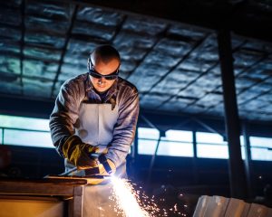 Worker cutting metal with plasma equipment on plant.